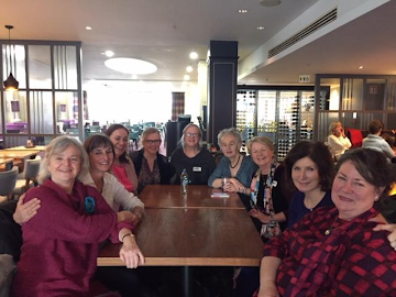 Group photo of MTAI members around a table in a restaurant, smiling at the camera
