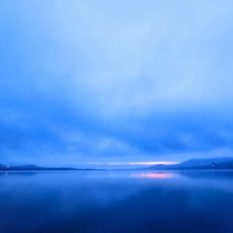 blue sky and sunrise over mountains at the edge of a lake